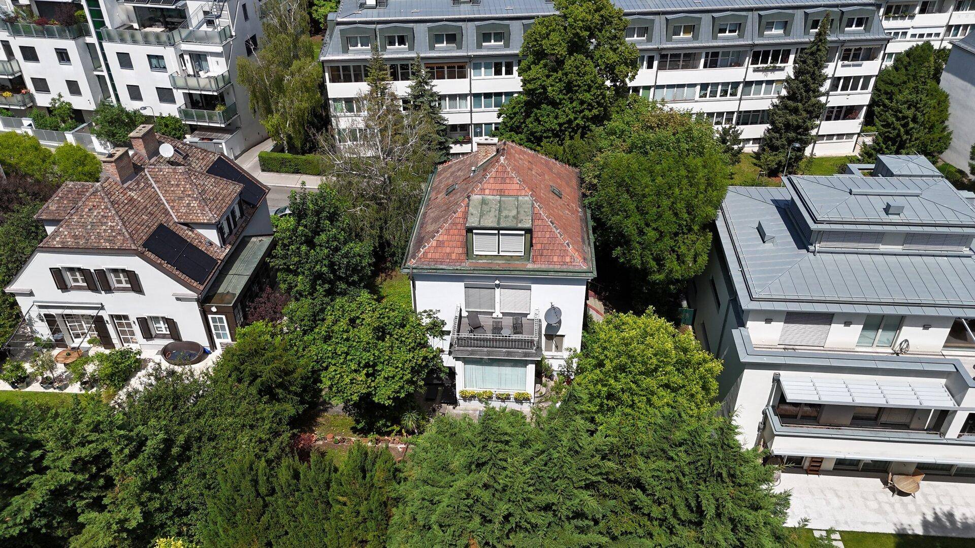 Weitläufige Luftaufnahme eines Wohnviertels mit Einfamilienhäusern und Mehrfamilienhäusern, umgeben von viel Grün.