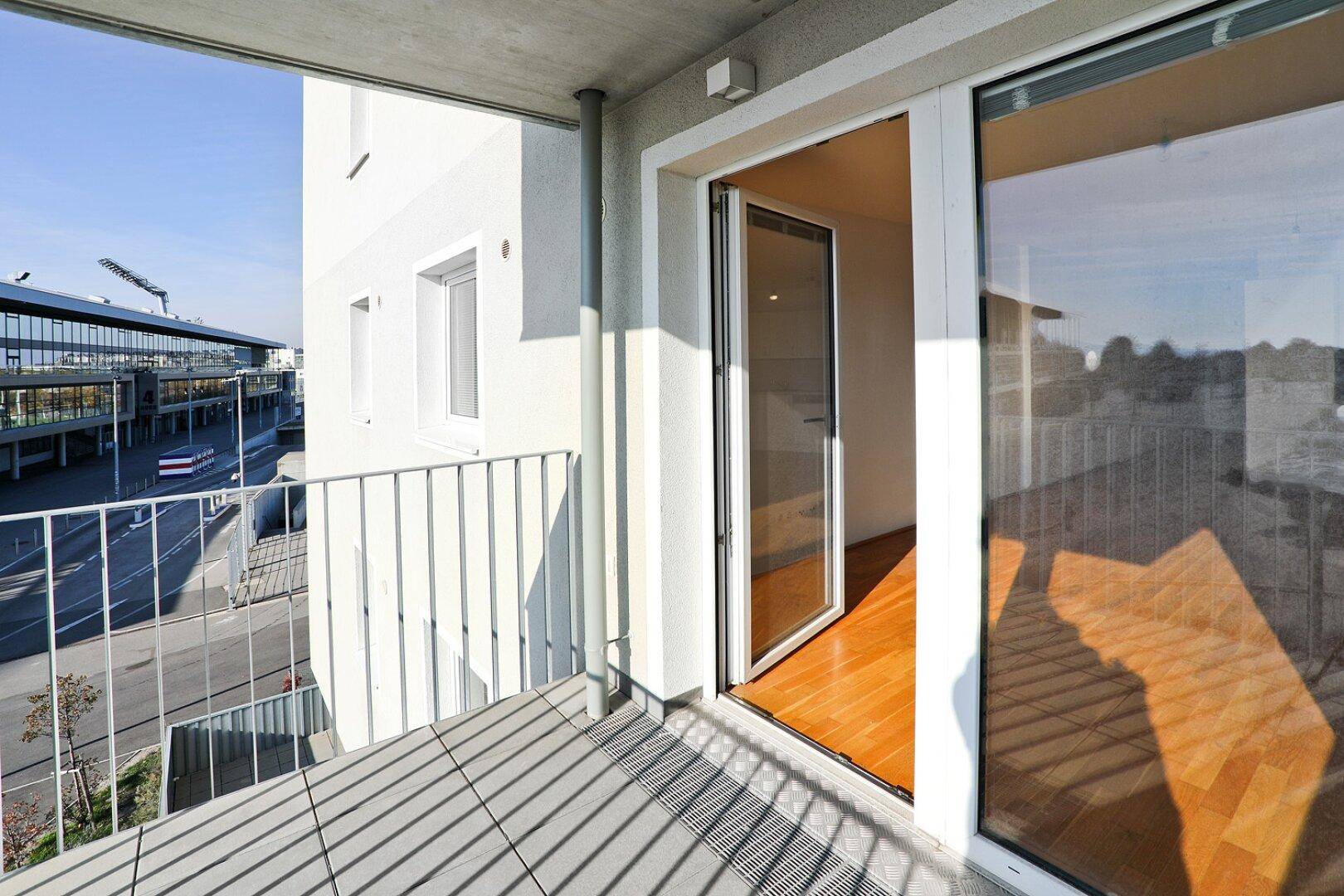 Heller Balkon mit Fliesenboden und Blick auf die umliegende Stadtlandschaft.