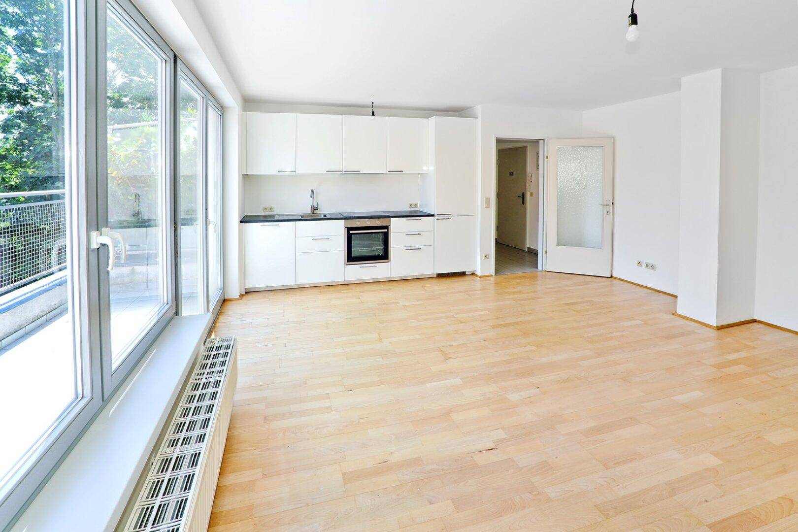 Lichtdurchfluteter Wohnbereich mit integrierter Küche und großzügigen Fensterfronten.