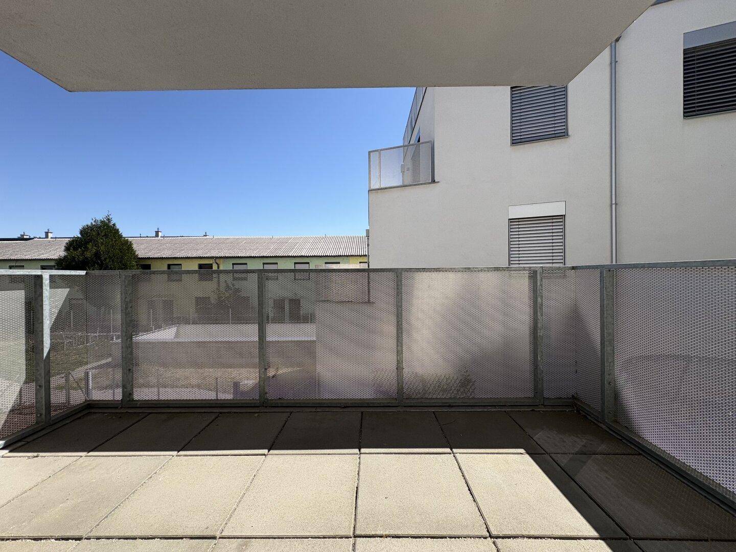 Geräumiger Balkon mit Fliesen und Metallgeländer, bietet einen Blick auf die Umgebung.