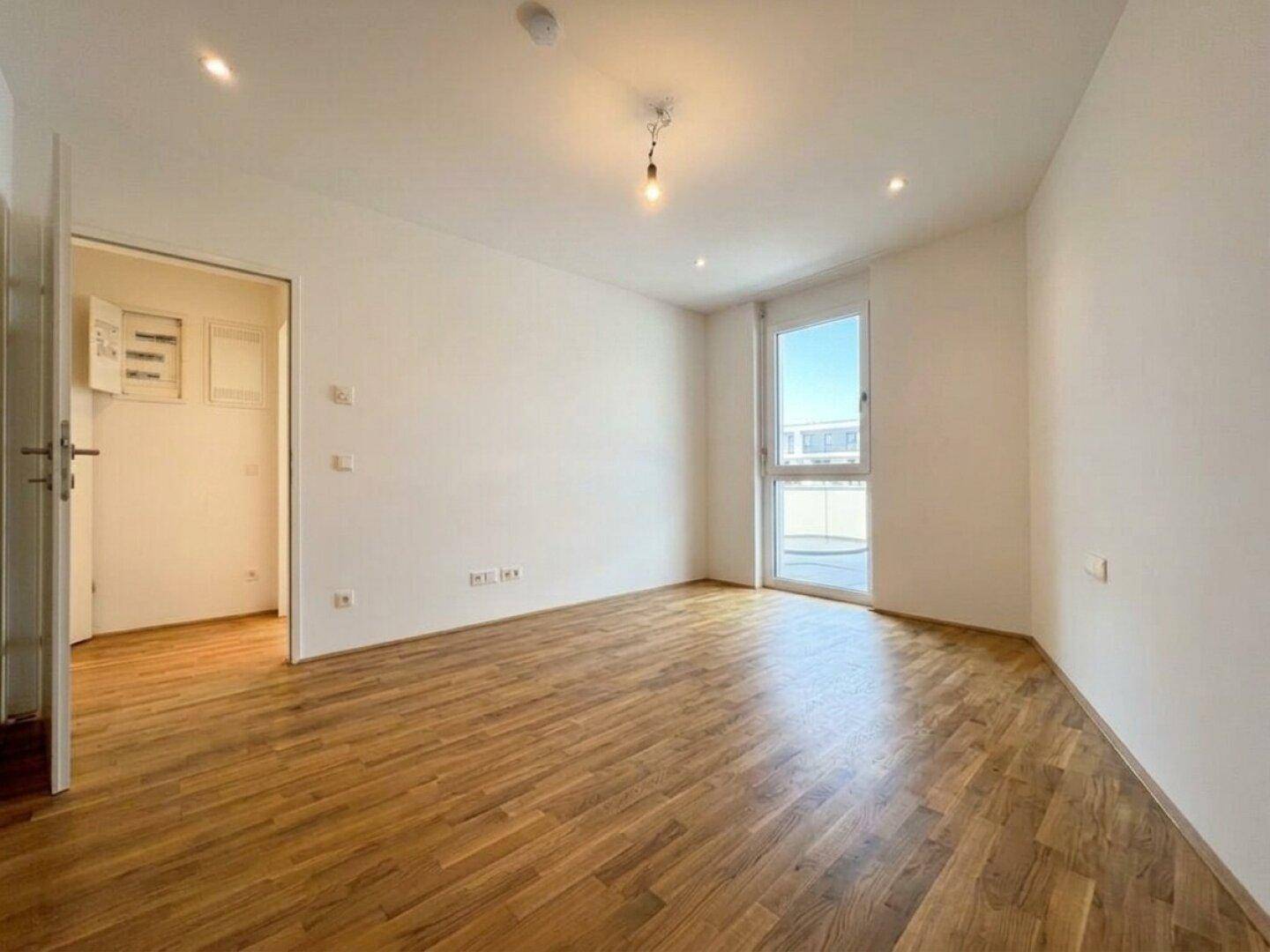 Heller Raum mit Parkettboden und Zugang zu einem Außenbereich, ideal als Schlafzimmer nutzbar.