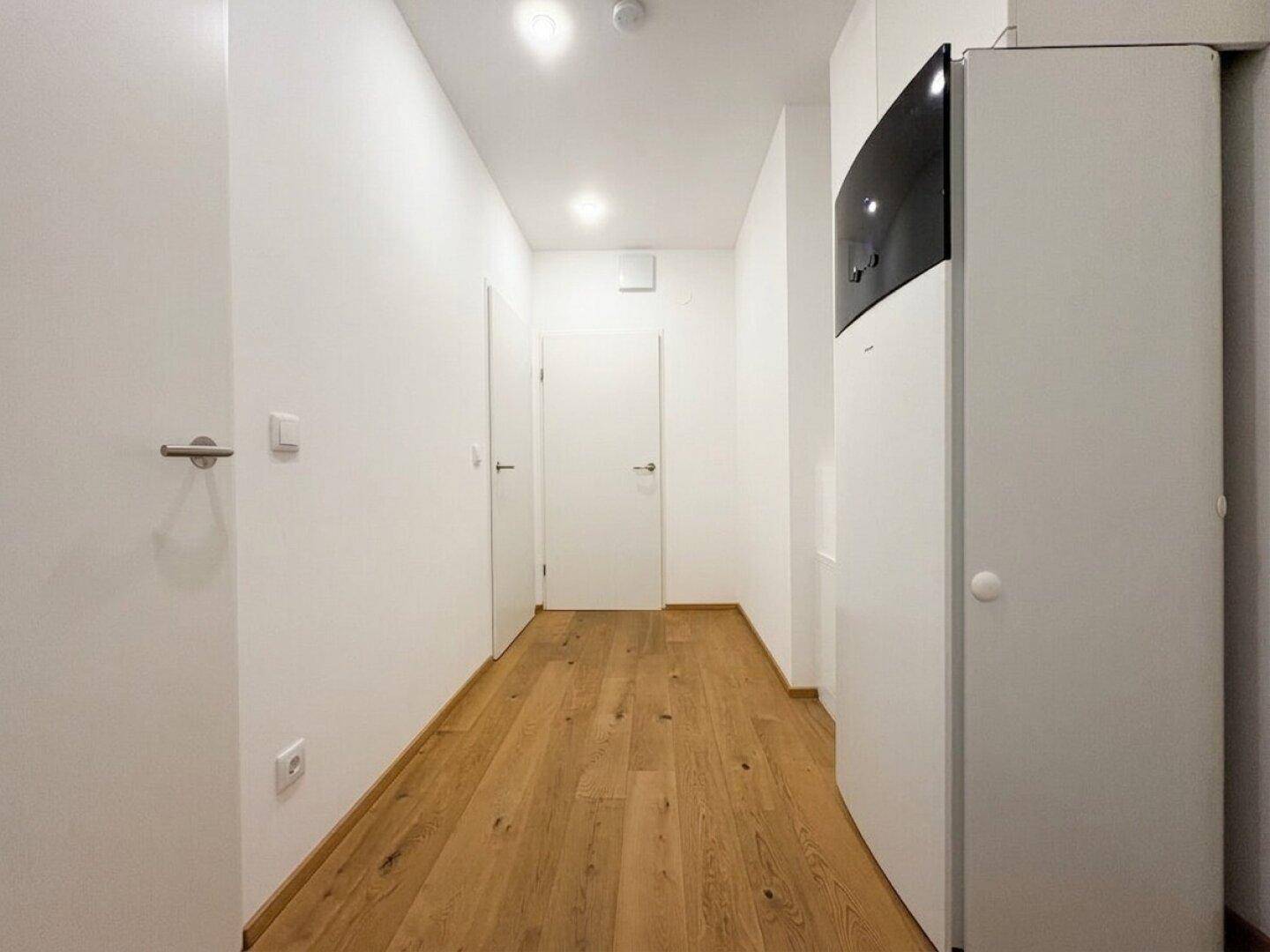 Heller Flur mit Holzboden, Einbauschrank und moderner Heizungsanlage.