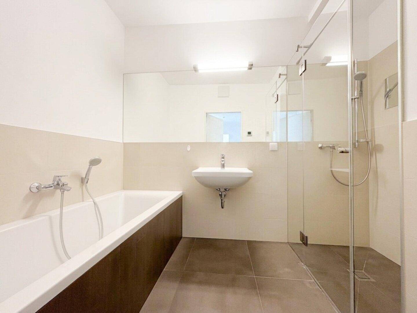 Modernes Badezimmer mit Badewanne, separater Dusche und großem Spiegel.