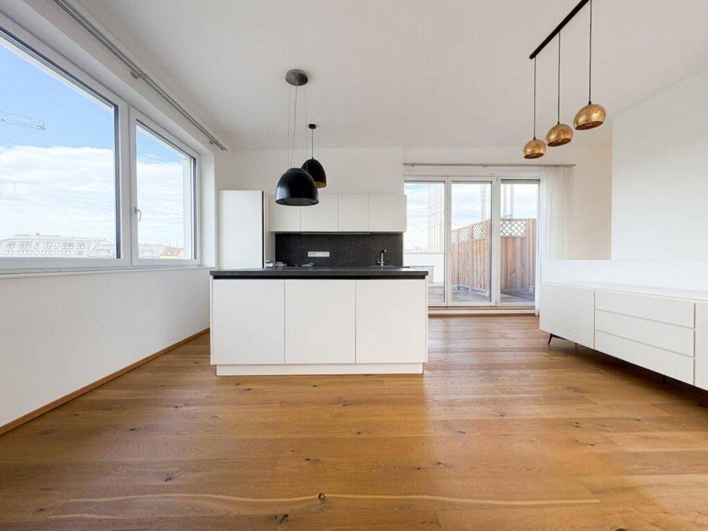 Lichtdurchfluteter Wohnbereich mit integrierter Küche, Holzboden und Zugang zur Dachterrasse.