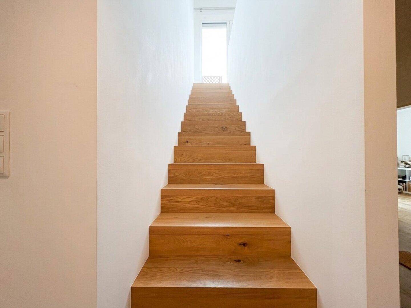Helle Holztreppe mit minimalistischem Design, die zu den oberen Etagen führt.