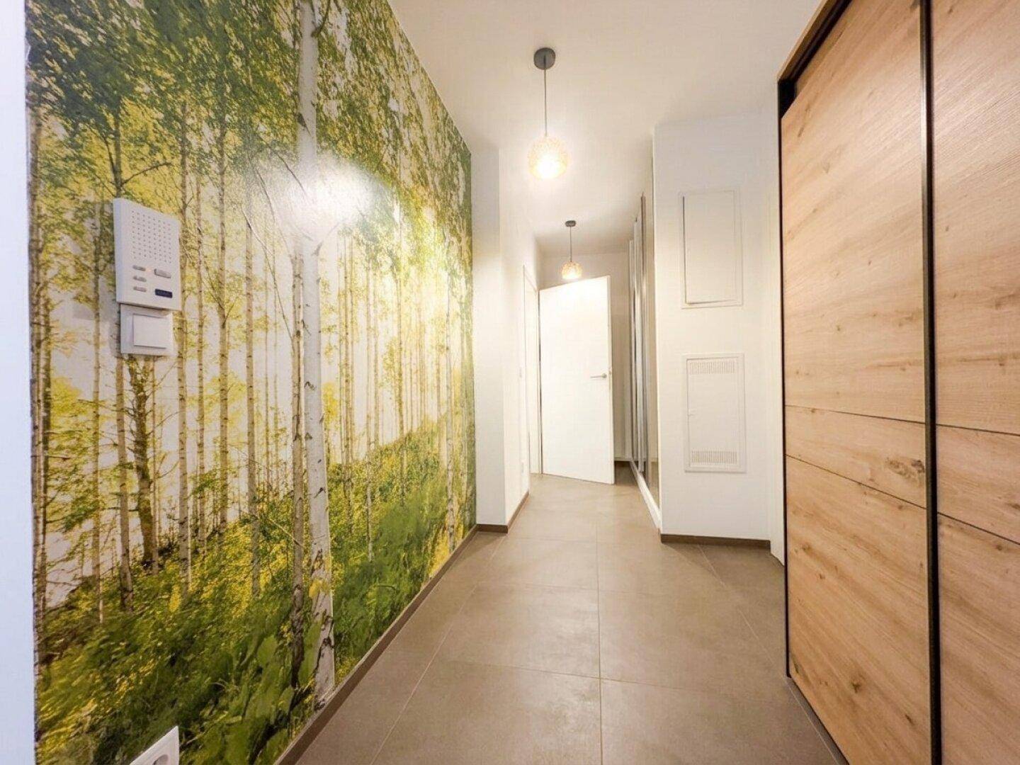 Moderner Flur mit Waldmotiv-Tapete, Fliesenboden und integriertem Kleiderschrank.