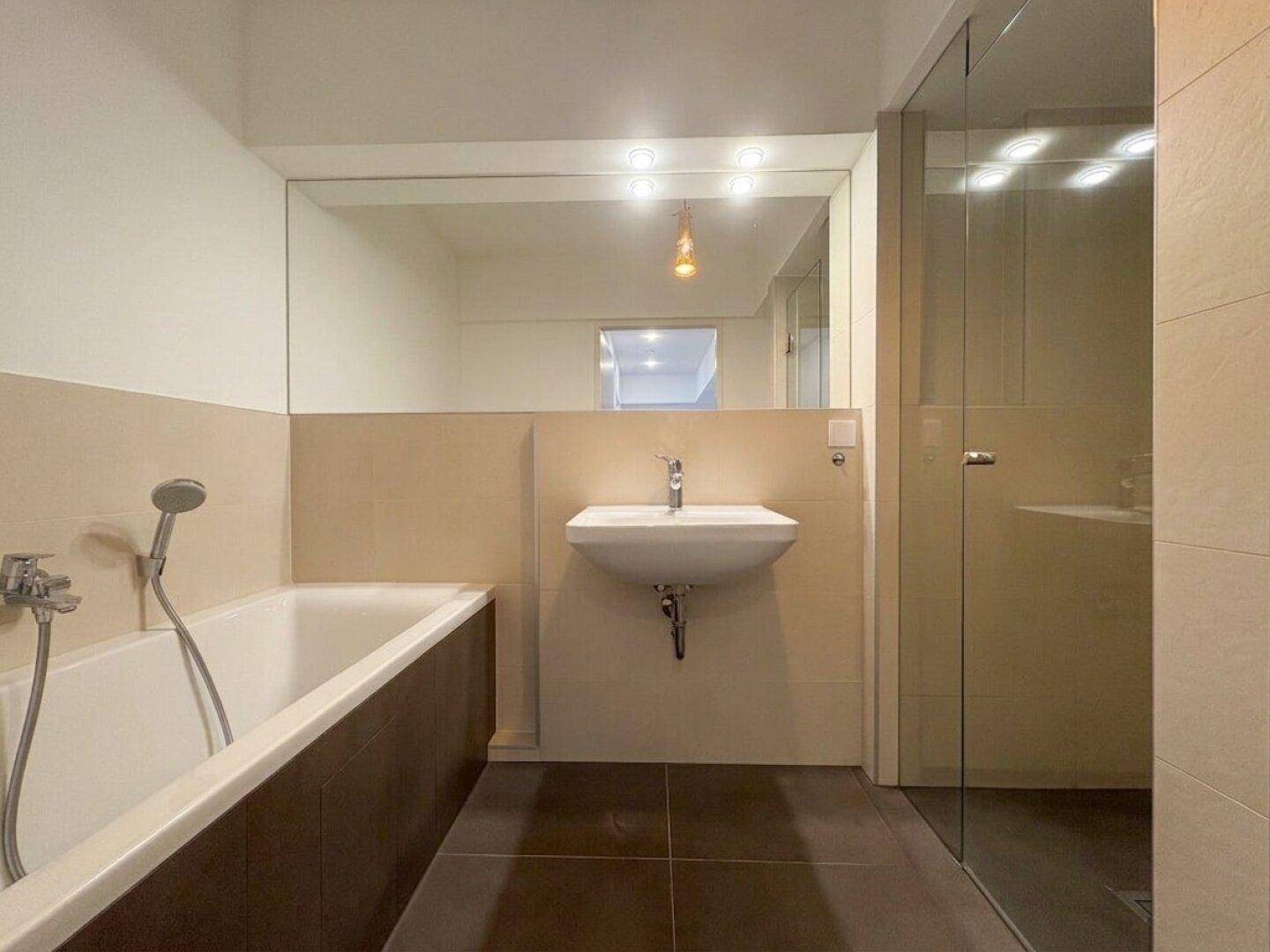 Modernes Badezimmer mit Badewanne, Waschbecken und separater Duschkabine.