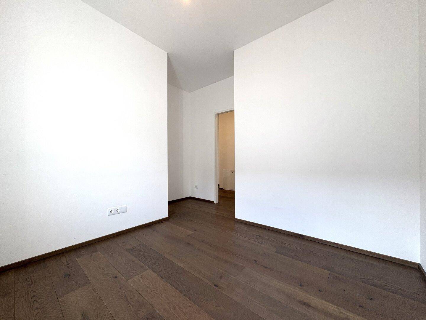 Leerer Raum mit Holzboden und weiß gestrichenen Wänden, bietet flexible Gestaltungsmöglichkeiten.