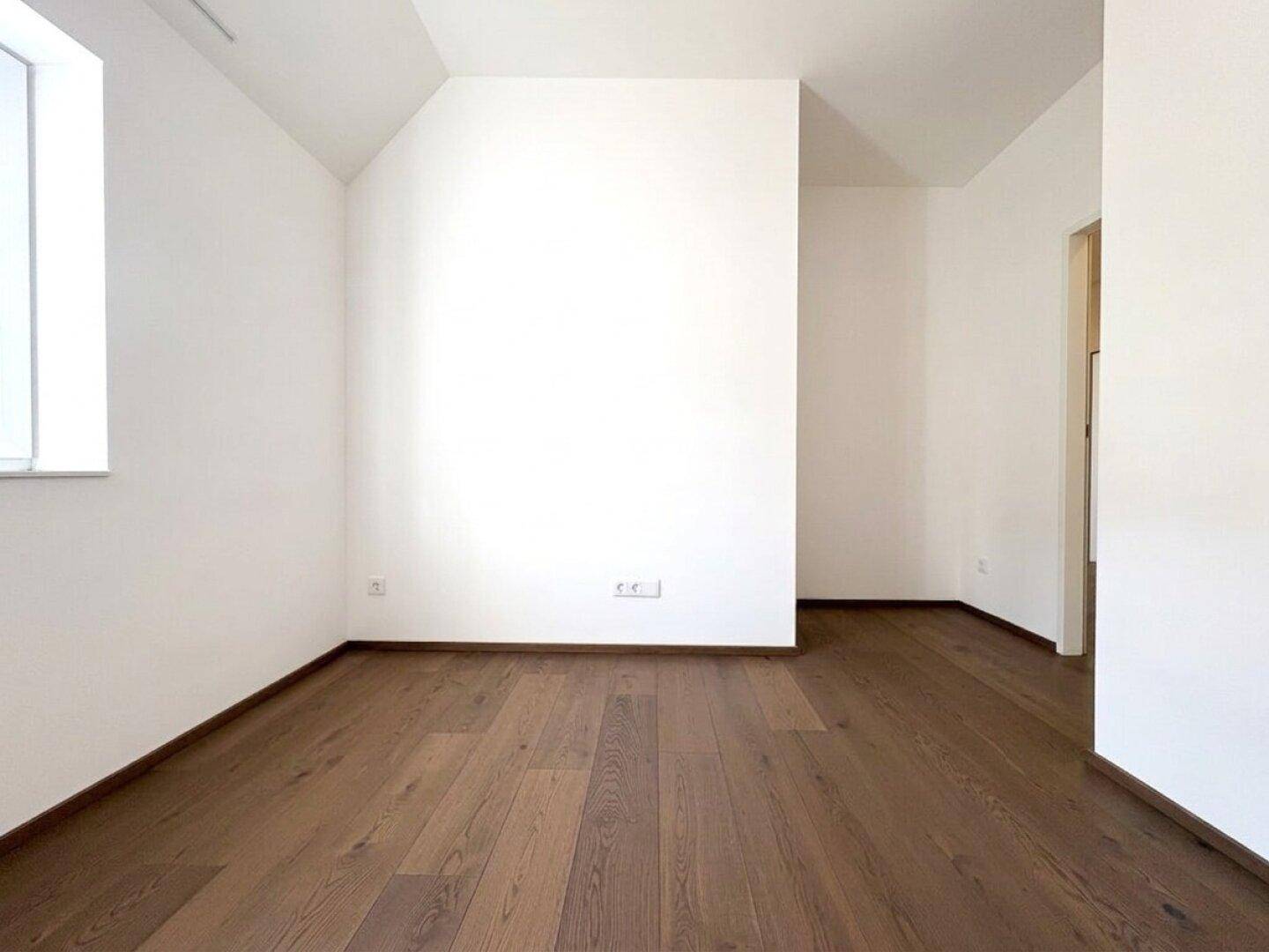 Unmöblierter Raum mit Holzboden und einem Fenster, ideal für individuelle Einrichtungsideen.
