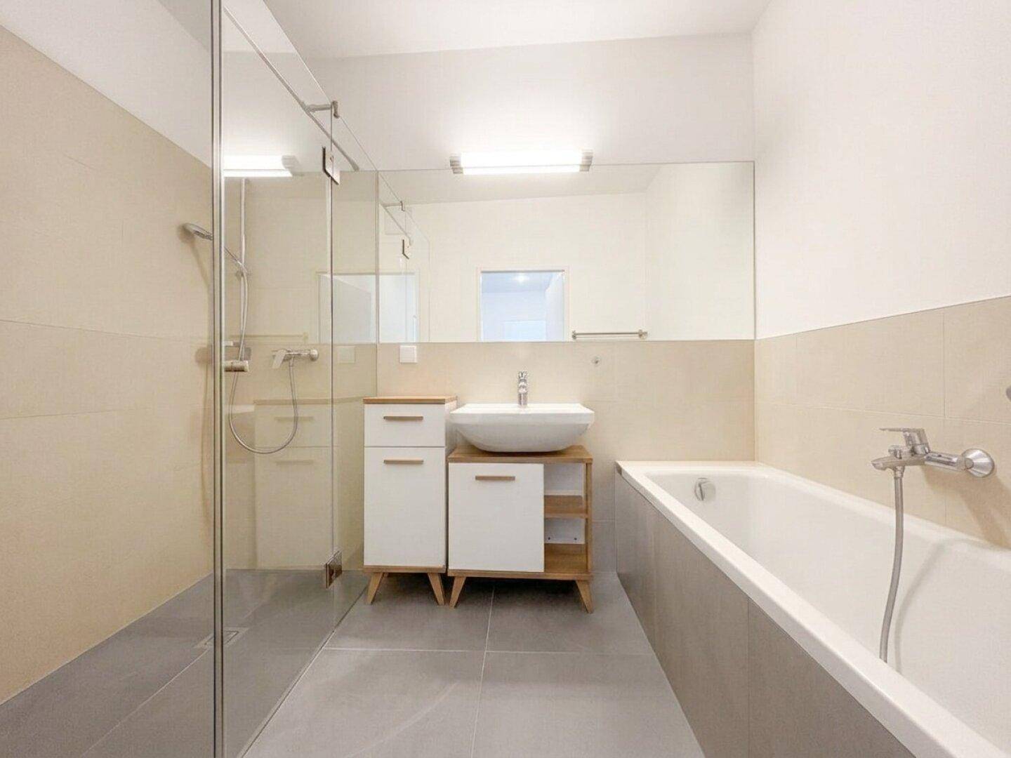 Modernes Badezimmer mit Badewanne, Dusche und stilvollem Waschbecken, in hellen Farbtönen gehalten.