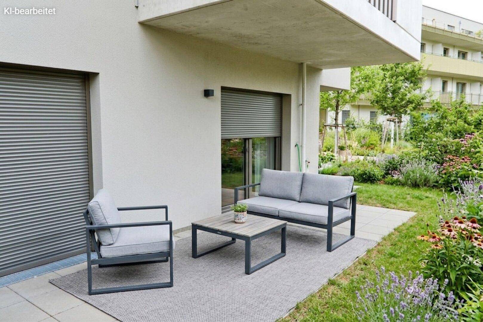 Kleine, möblierte Terrasse mit Blick ins Grüne und Rollläden an den Fenstern des Neubaus.