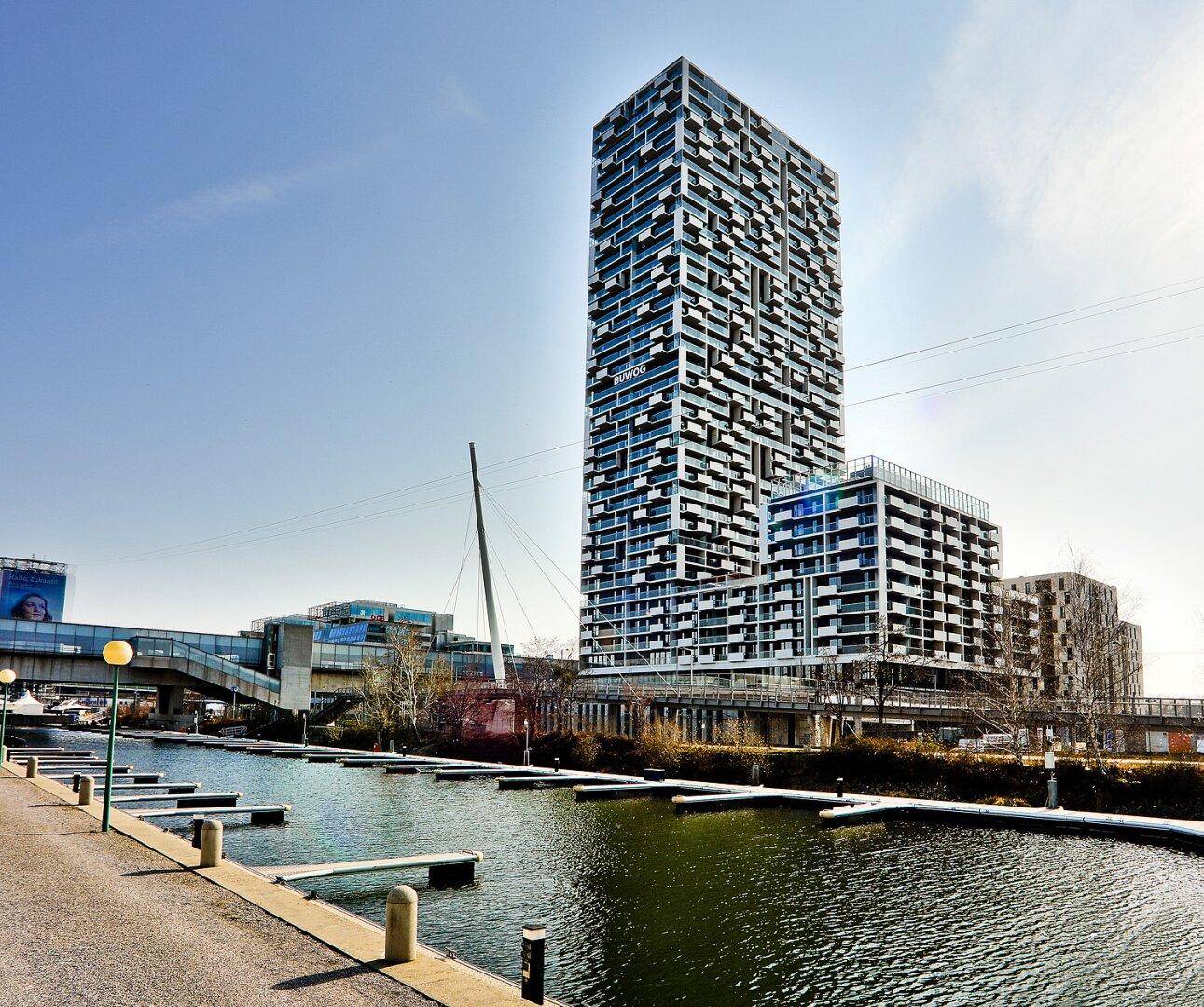 Beeindruckendes modernes Hochhaus am Wasser mit markanter Architektur und vielen Fenstern.