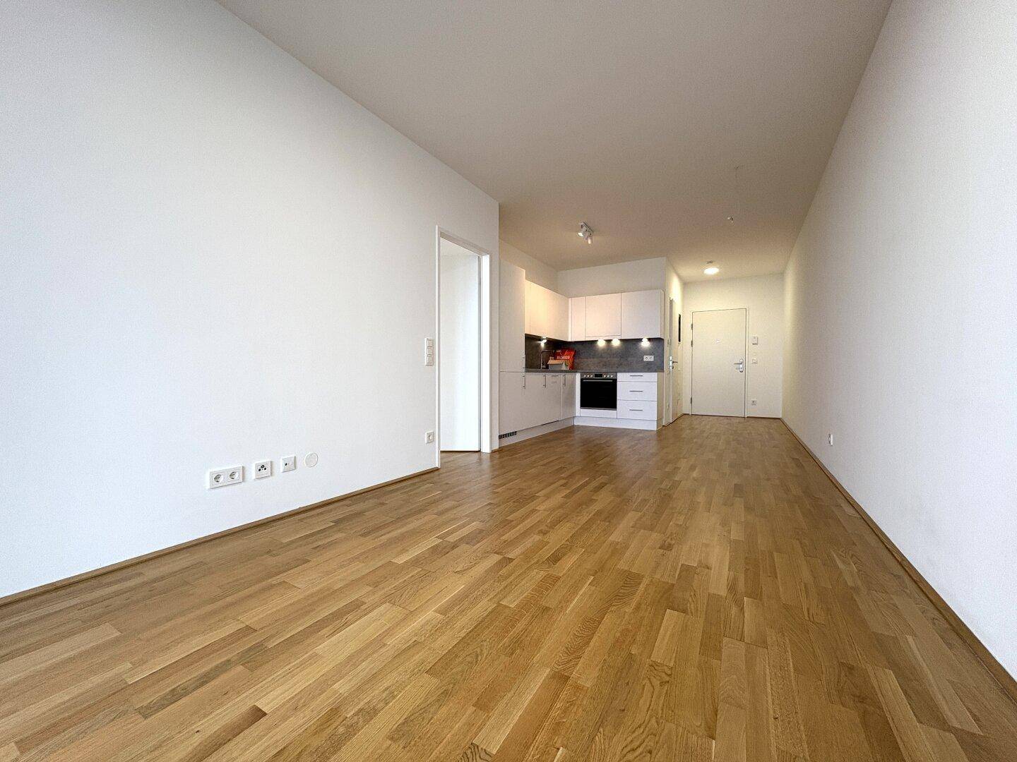 Geräumiger Wohnbereich mit Holzboden und offener Küchenzeile in modernem Design.