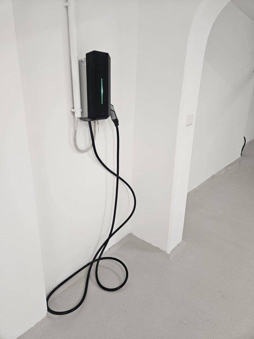 Moderne Ladestation für Elektrofahrzeuge an einer weißen Wand in einem hellen Bereich.