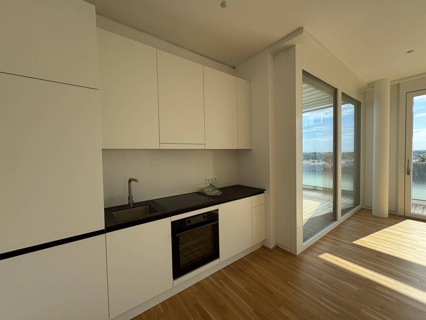 Helle Küchenzeile mit minimalistischem Design und direktem Zugang zu den großzügigen Außenbereichen.