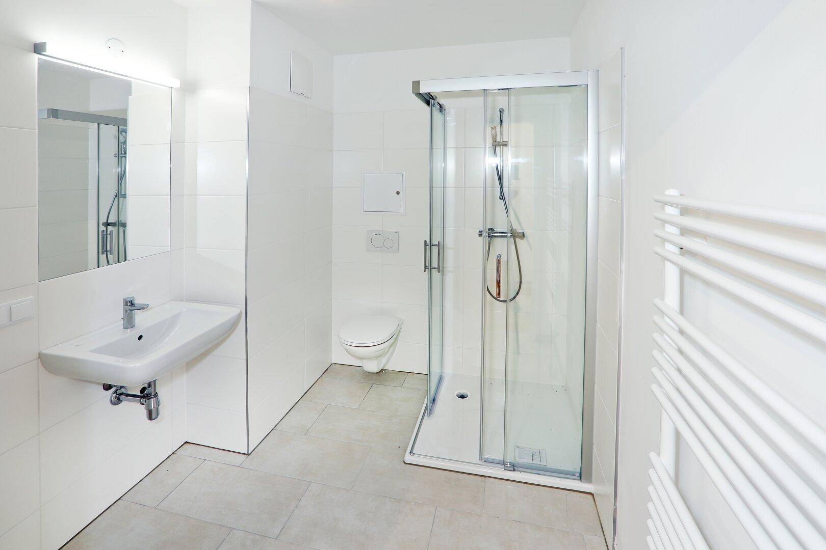 Modernes Badezimmer mit Dusche, WC, Waschbecken und einem praktischen Handtuchheizkörper.