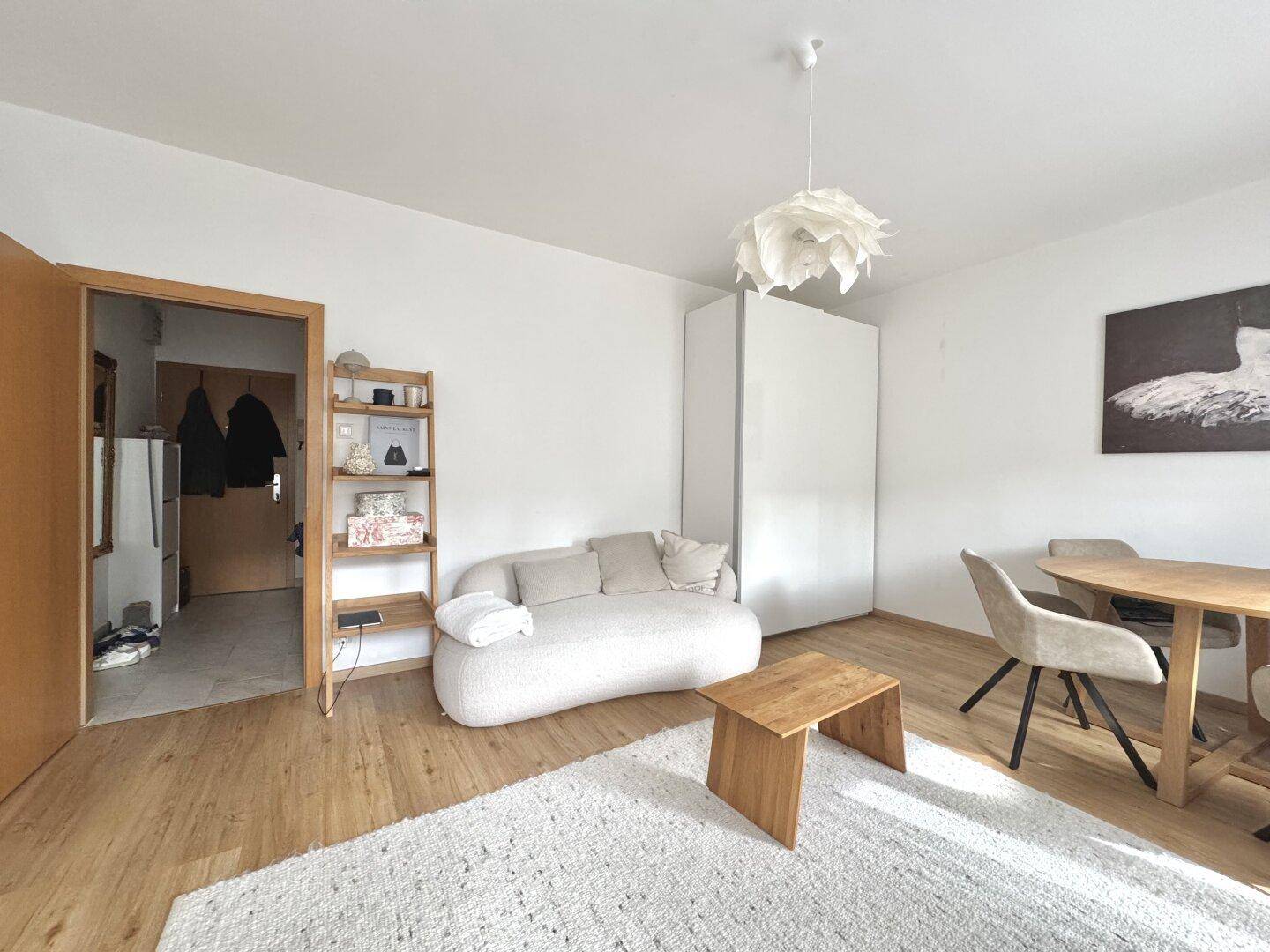 Offener Wohn- und Essbereich mit Holzboden, Sofa und Esstisch.