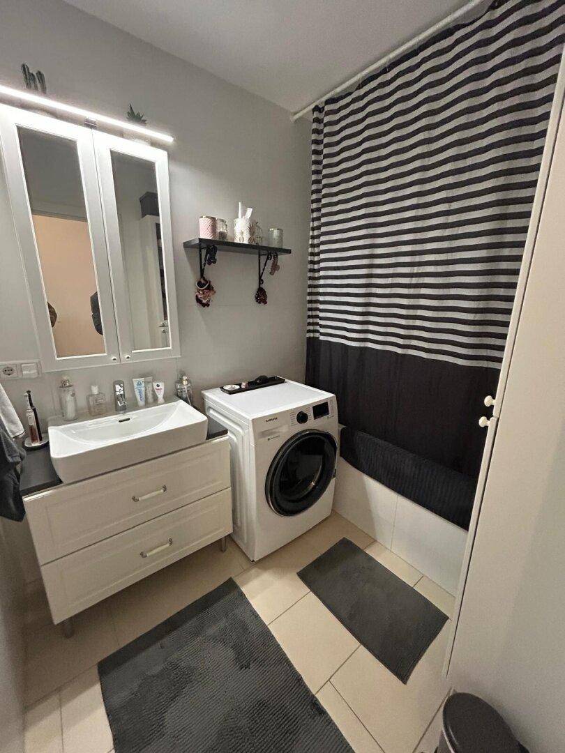 Modernes Badezimmer mit Waschbecken, Spiegelschrank, Badewanne und Waschmaschine.