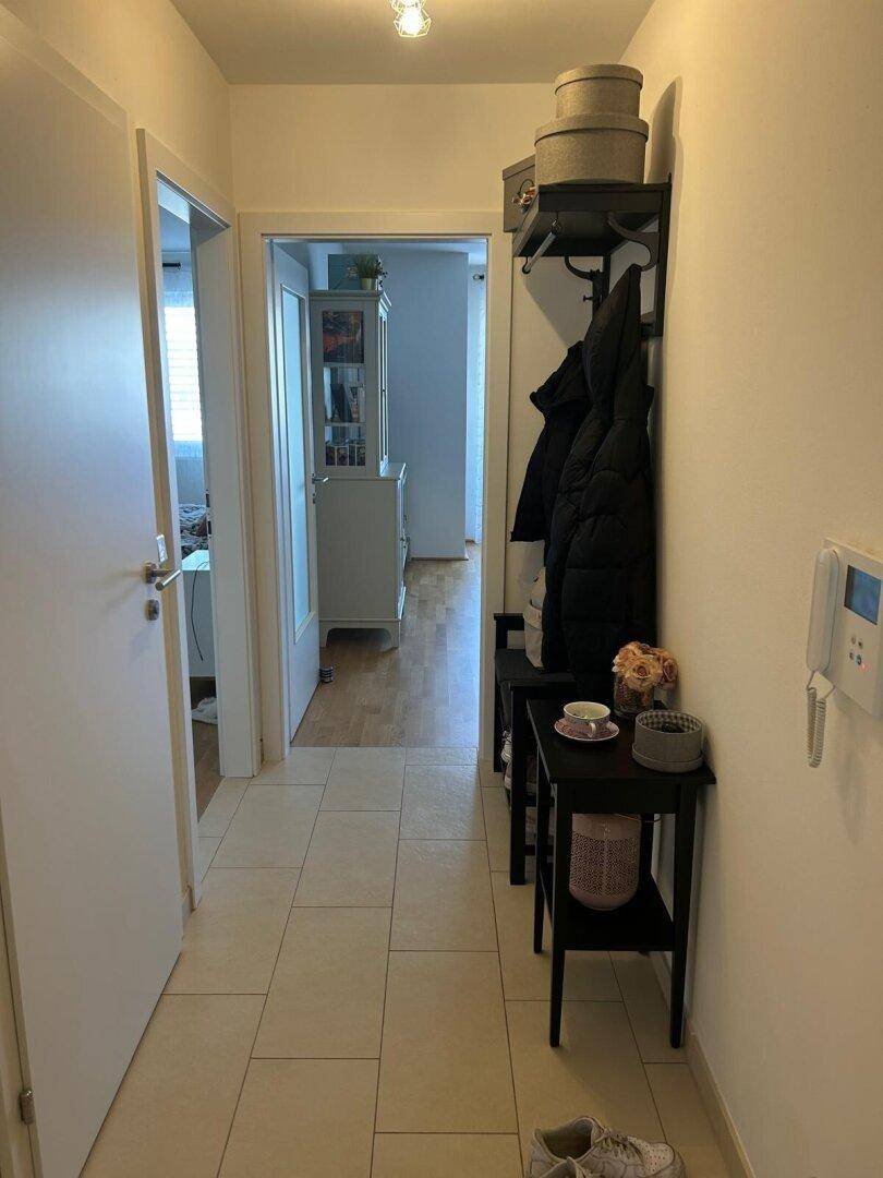 Heller Flur mit Fliesenboden, Garderobe und Zugang zu weiteren Räumen.