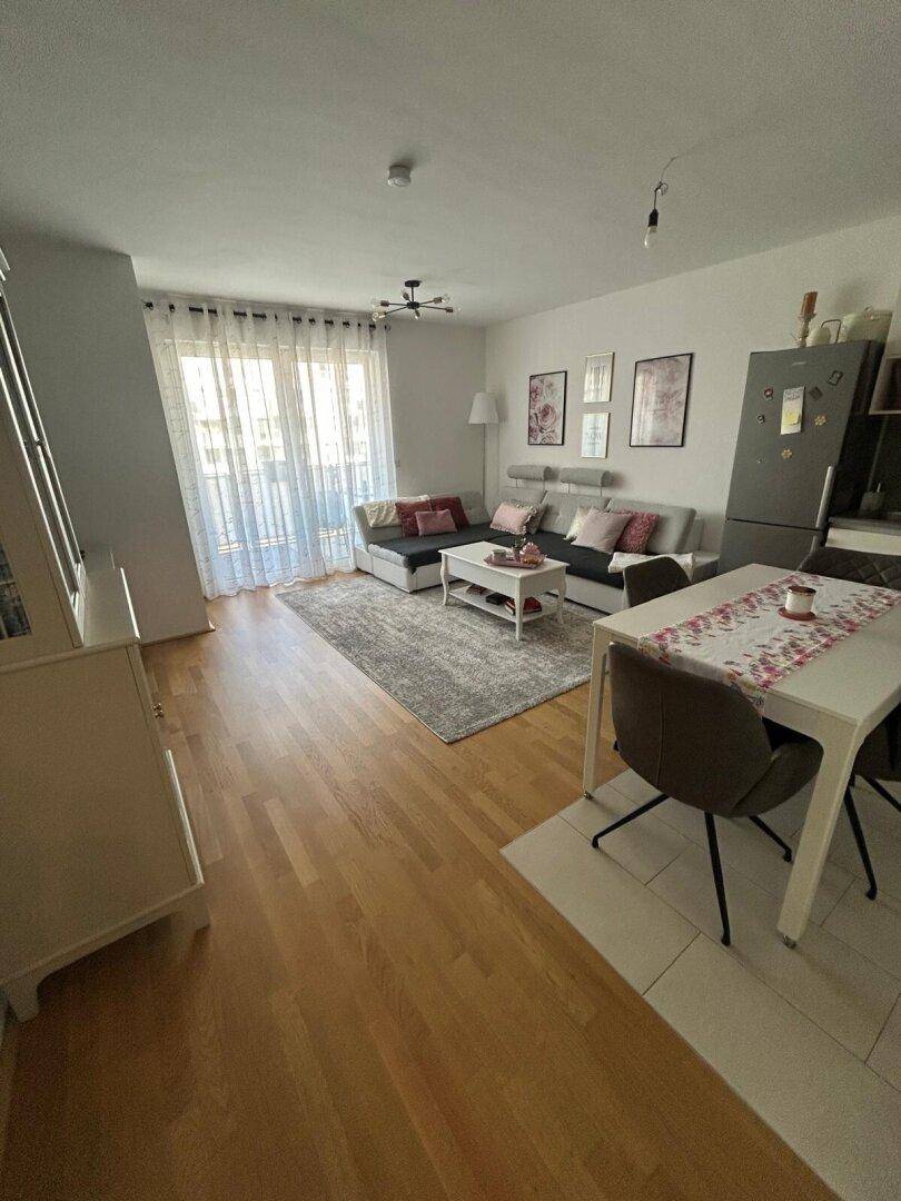 Offener Wohn- und Essbereich mit Sofa, Esstisch und hellem Holzboden.