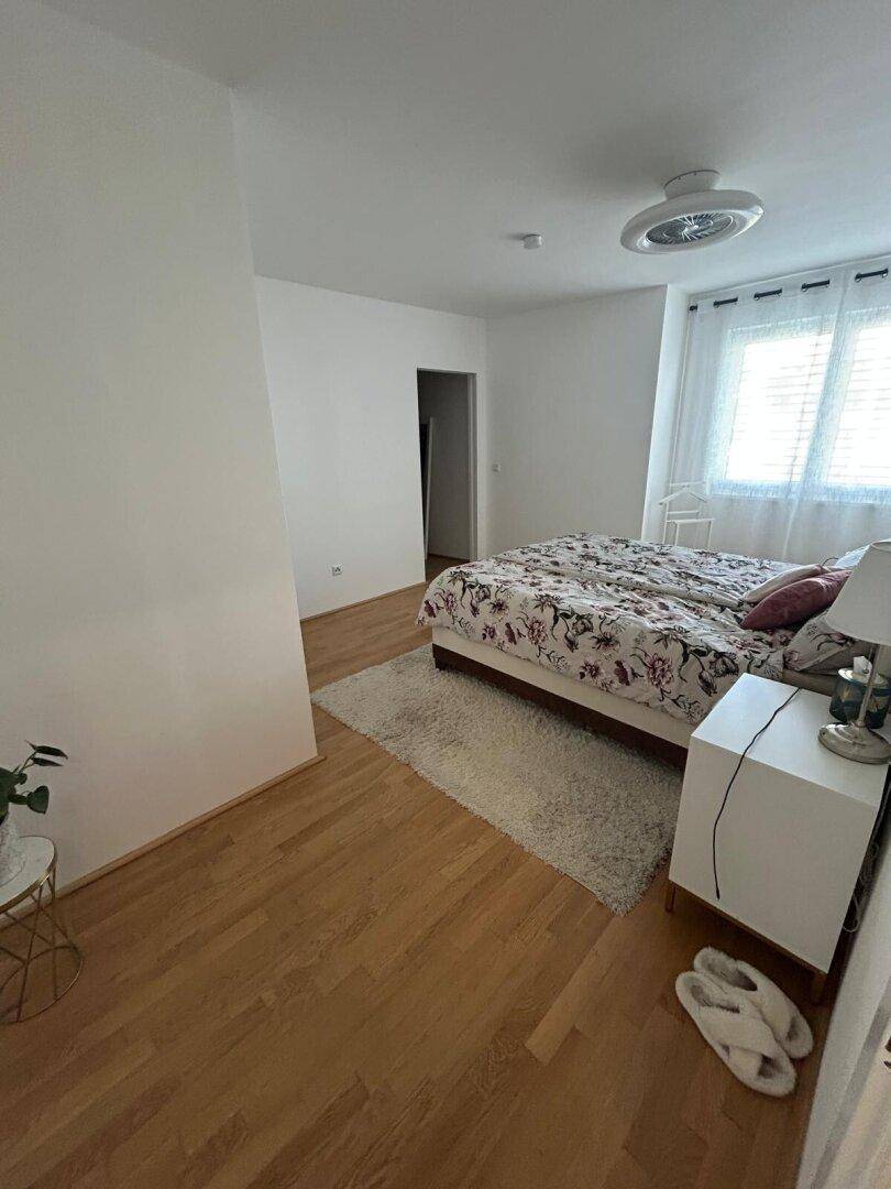 Helles Schlafzimmer mit Holzboden, großem Bett und Fenster für natürliches Licht.