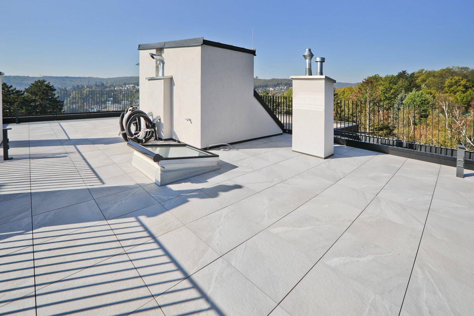Große Dachterrasse mit Oberlicht und weitem Blick in die Natur unter blauem Himmel.