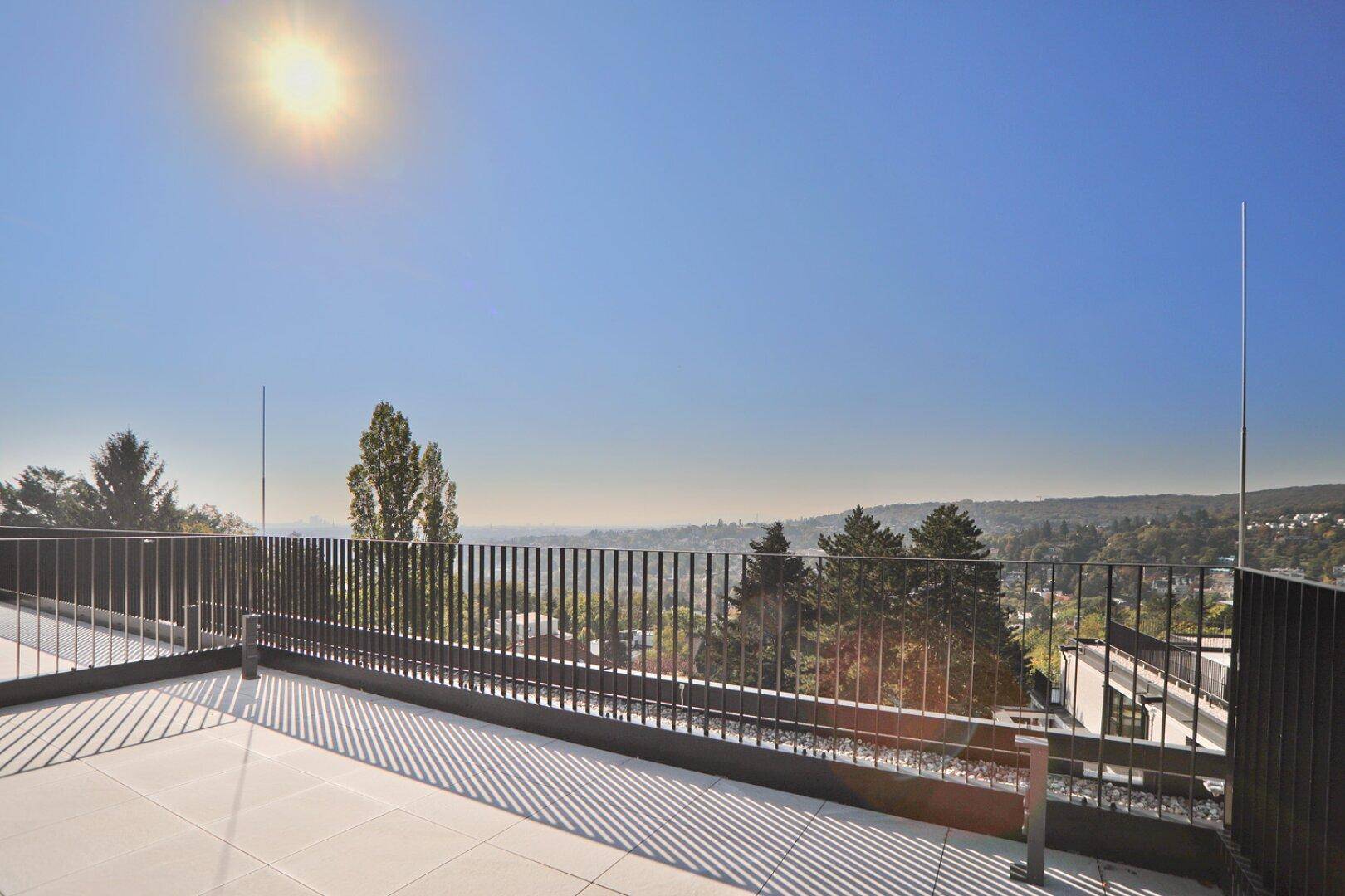 Sonnige Dachterrasse mit weitem Blick über die Landschaft und den klaren blauen Himmel.