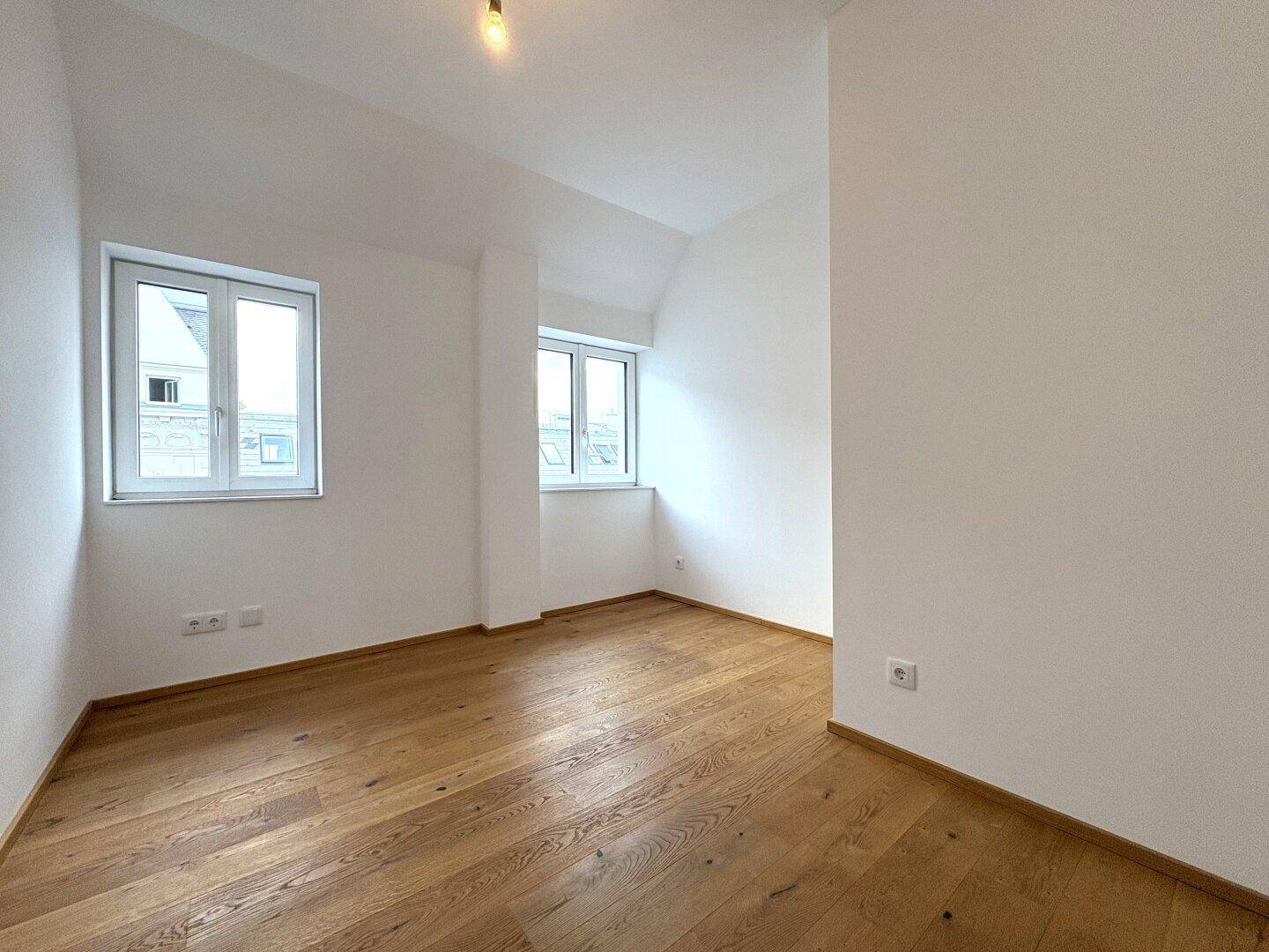 Geräumiges Schlafzimmer mit viel Tageslicht und elegantem Parkettboden, bereit zur individuellen Gestaltung.