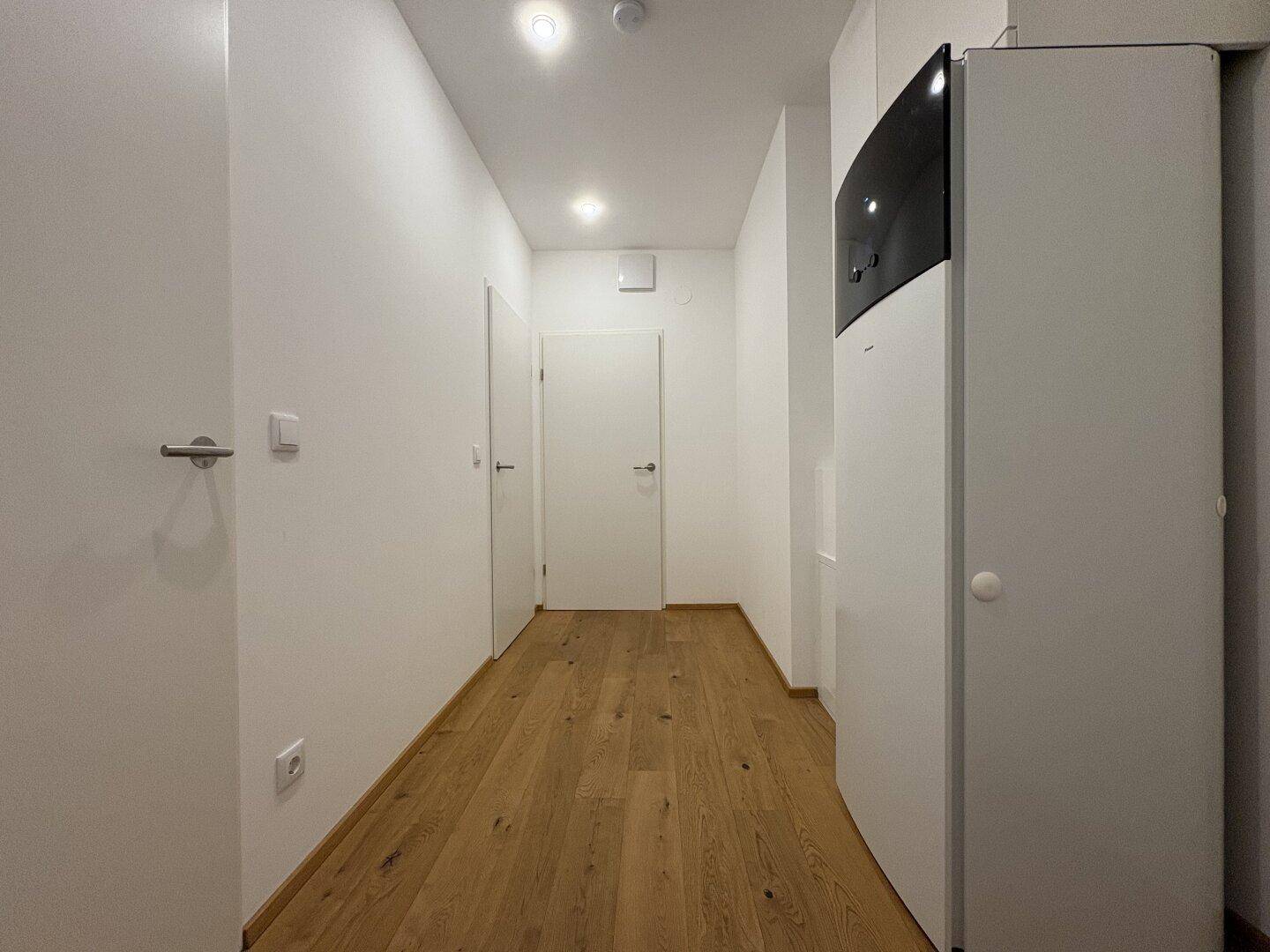 Heller Flur mit Holzparkett und integrierter Heizungsanlage, bietet Zugang zu den weiteren Räumen.
