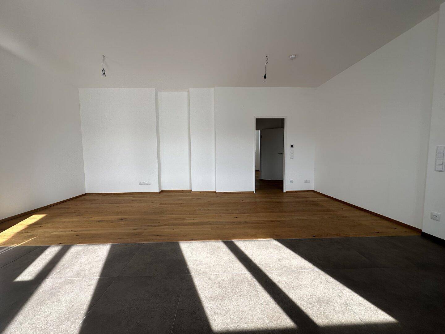 Geräumiger Wohnbereich mit hellem Parkettboden und viel Tageslicht, bereit zur individuellen Gestaltung.