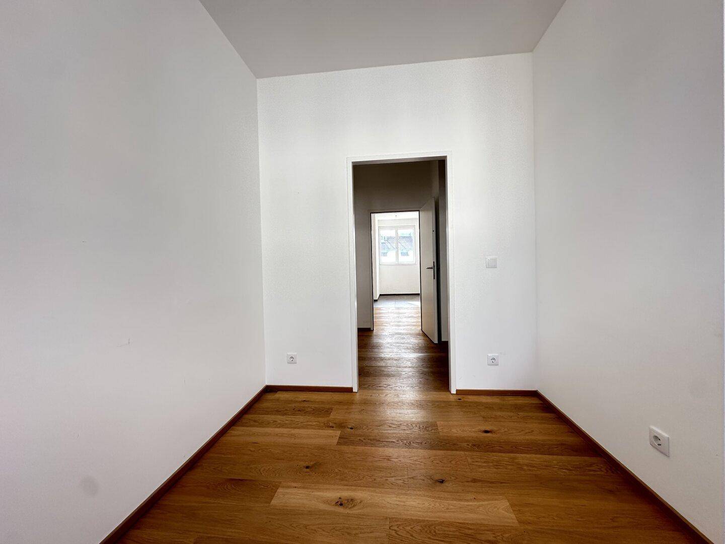 Freundliches Zimmer mit Parkettboden und Zugang zu einem weiteren Raum, vielseitig nutzbar.
