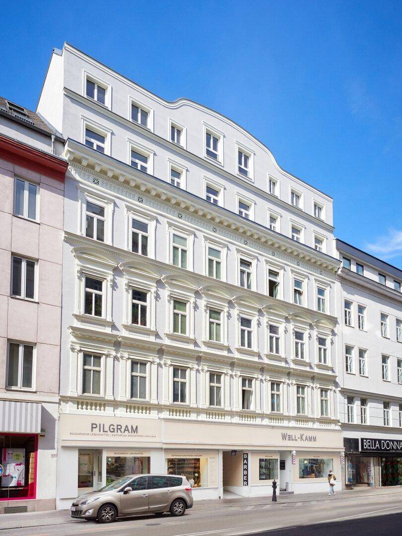 Historisches Gebäude mit klassischer Architektur und modernem Dachausbau in urbaner Umgebung.