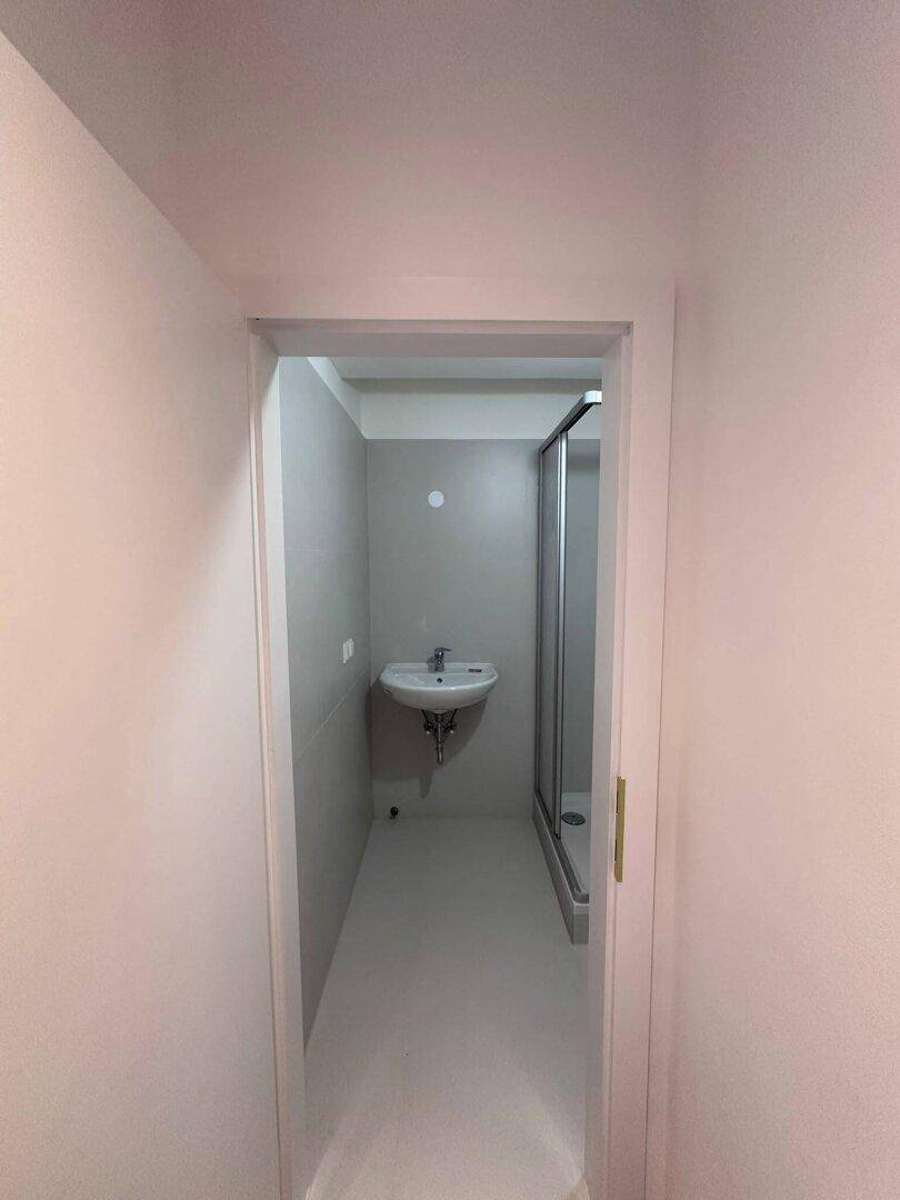 Helles Badezimmer mit Waschbecken und Duschkabine, bereit zur Nutzung.