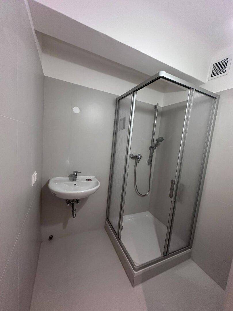 Funktionales Badezimmer mit Waschbecken und einer kompakten Duschkabine.
