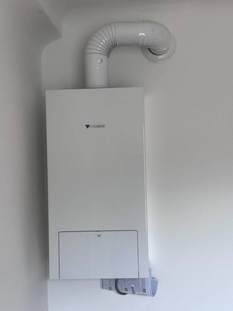 Nahaufnahme einer modernen Junkers Gastherme an einer weißen Wand montiert.