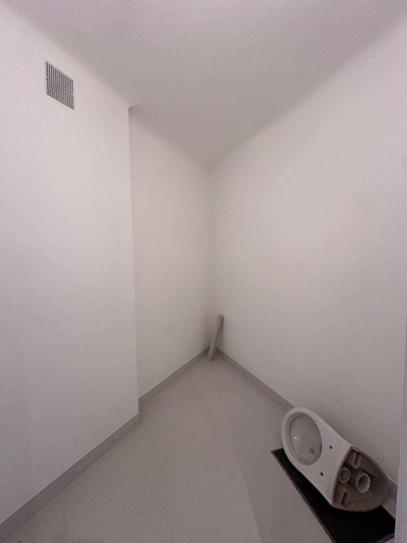 Leerer kleiner Raum, möglicherweise für ein WC, mit Lüftungsgitter an der Decke.
