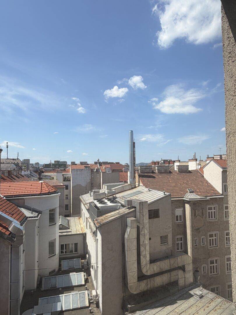 Weitläufiger Blick über die Dächer der Stadt unter einem klaren blauen Himmel.