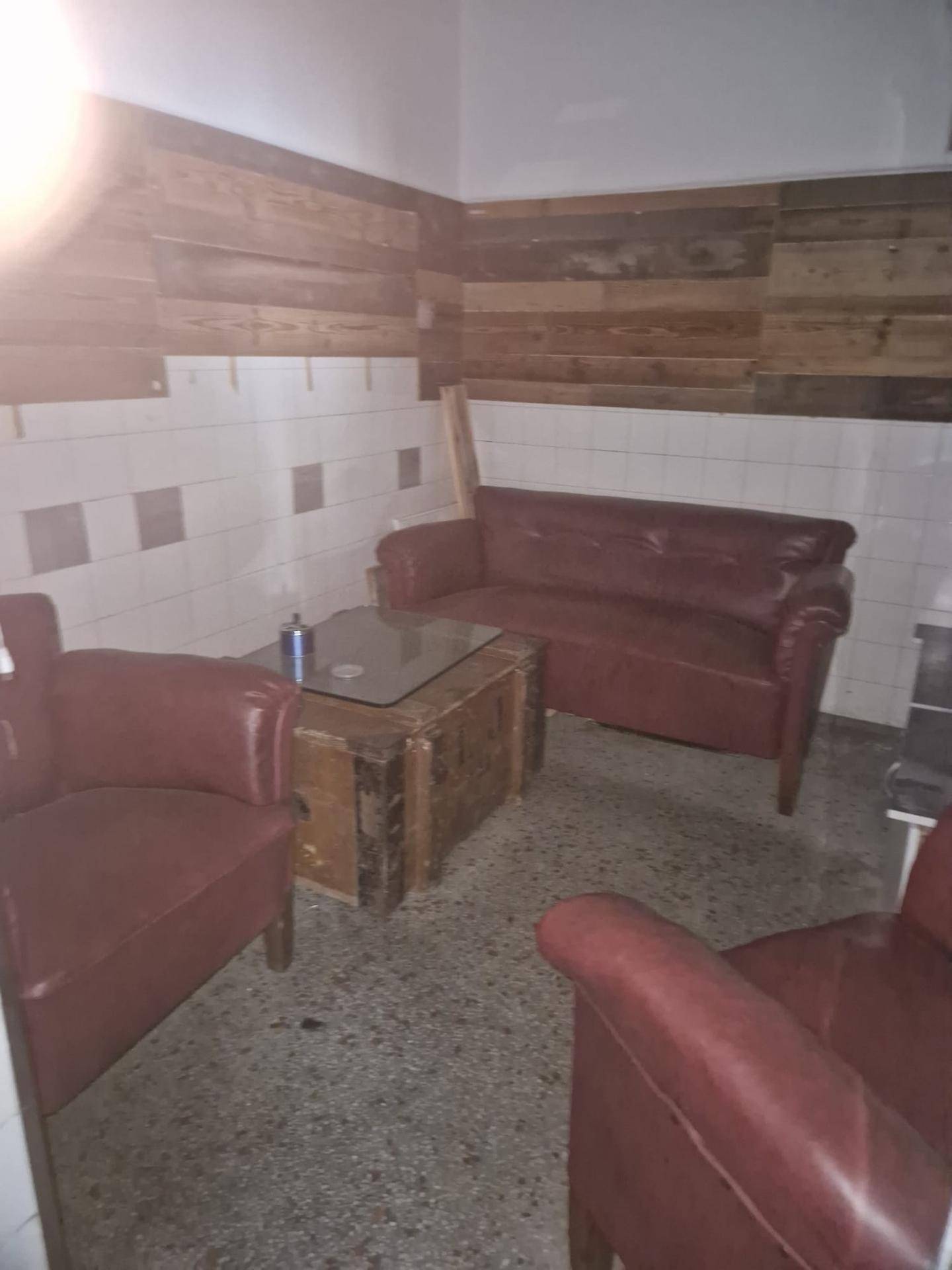 Gemütlicher Loungebereich mit roten Ledersofas, einem Holztisch und einer Wandverkleidung aus Holz.