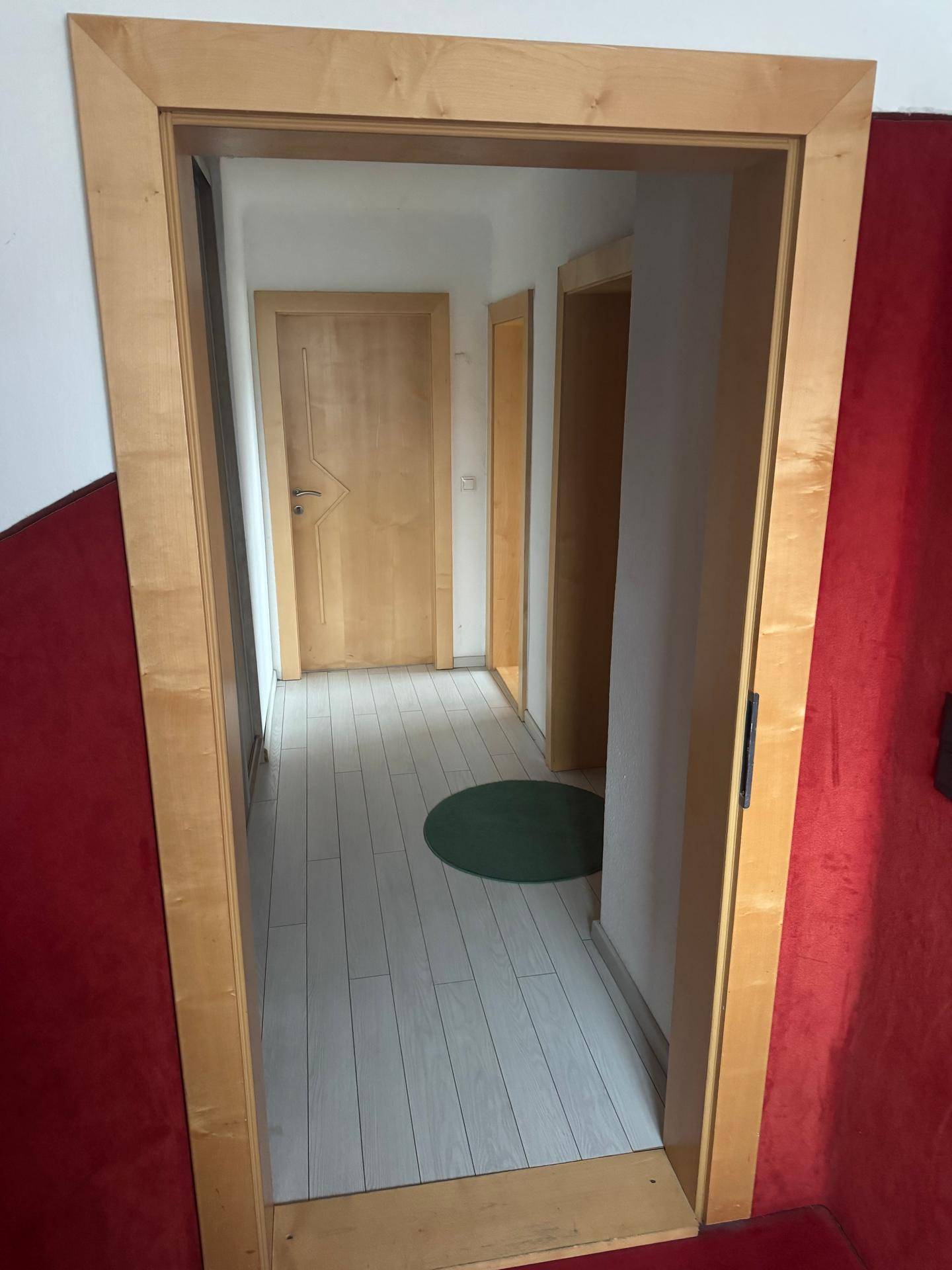 Heller Flur mit Holztüren und hellem Boden, der zu weiteren Räumen im Haus führt.