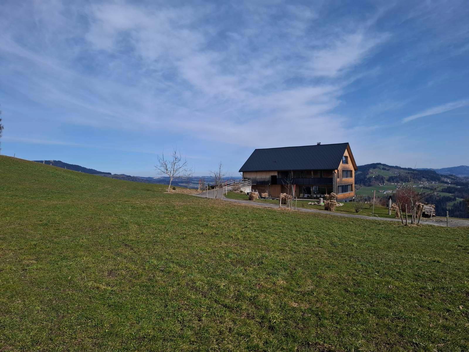 Das moderne Holzhaus liegt idyllisch auf einer Anhöhe mit weitem Blick über die grüne Landschaft.