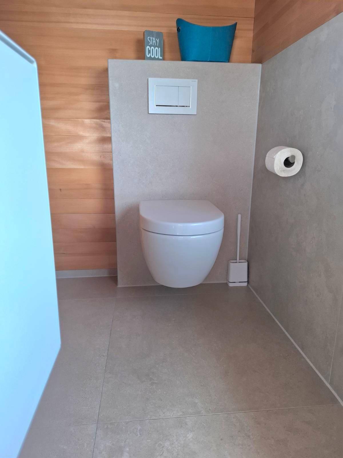 Modernes WC mit Wand-WC und hellen Fliesen, kombiniert mit Holzwänden.