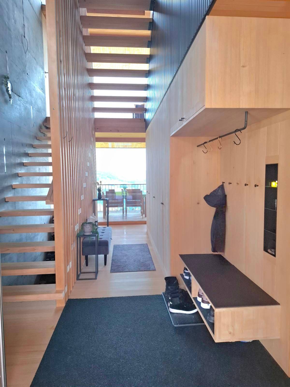 Eingangsbereich mit Garderobe, Sitzbank und Blick auf den Balkon mit Bergblick.