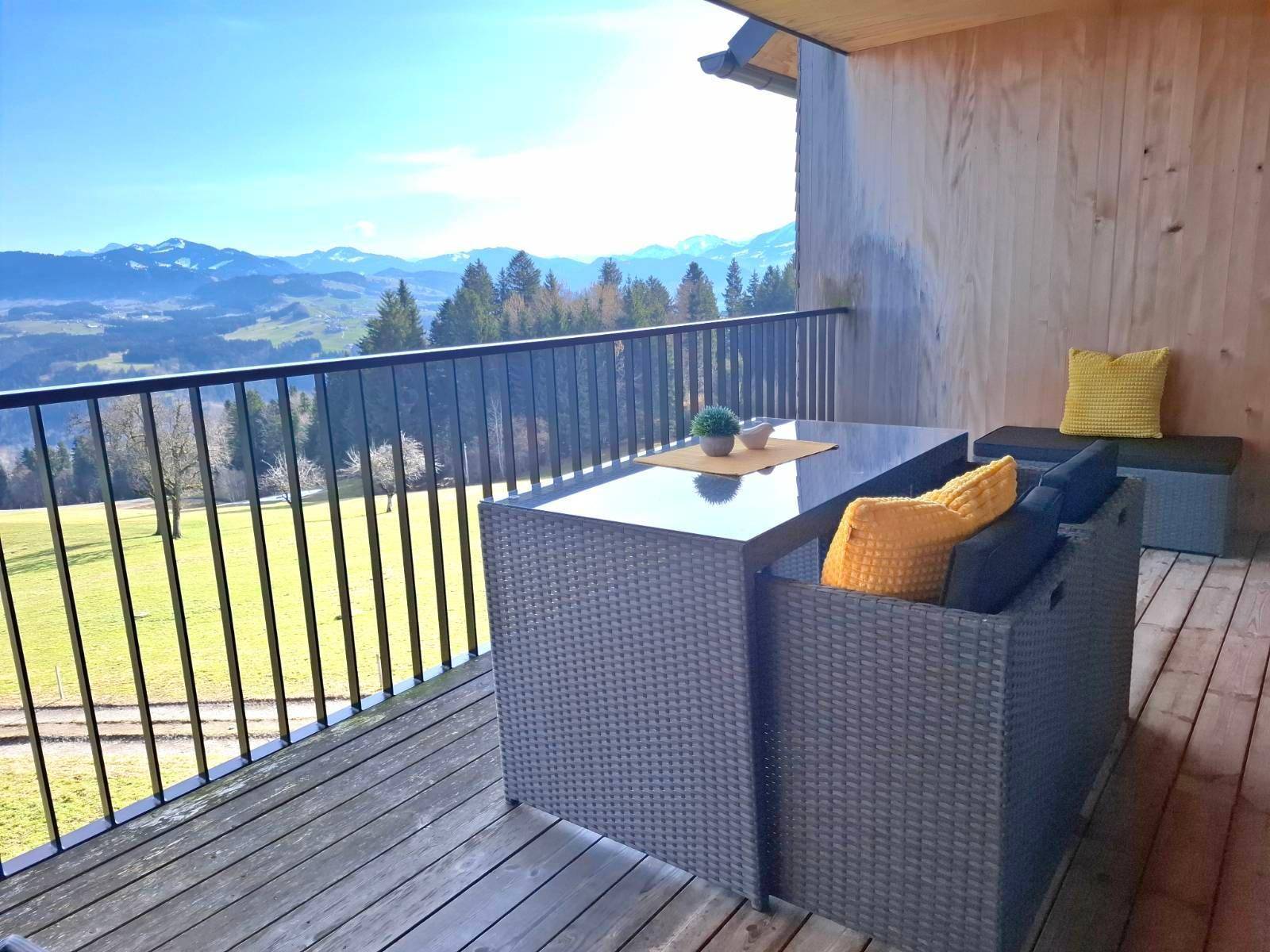 Gemütlicher Balkon mit Sitzgelegenheiten und Panoramablick auf die Berge und grüne Täler.