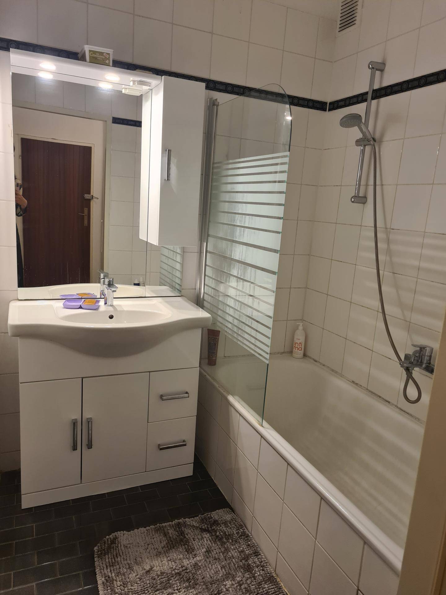Badezimmer mit Badewanne, Duschvorrichtung, Waschbecken und Spiegelschrank.