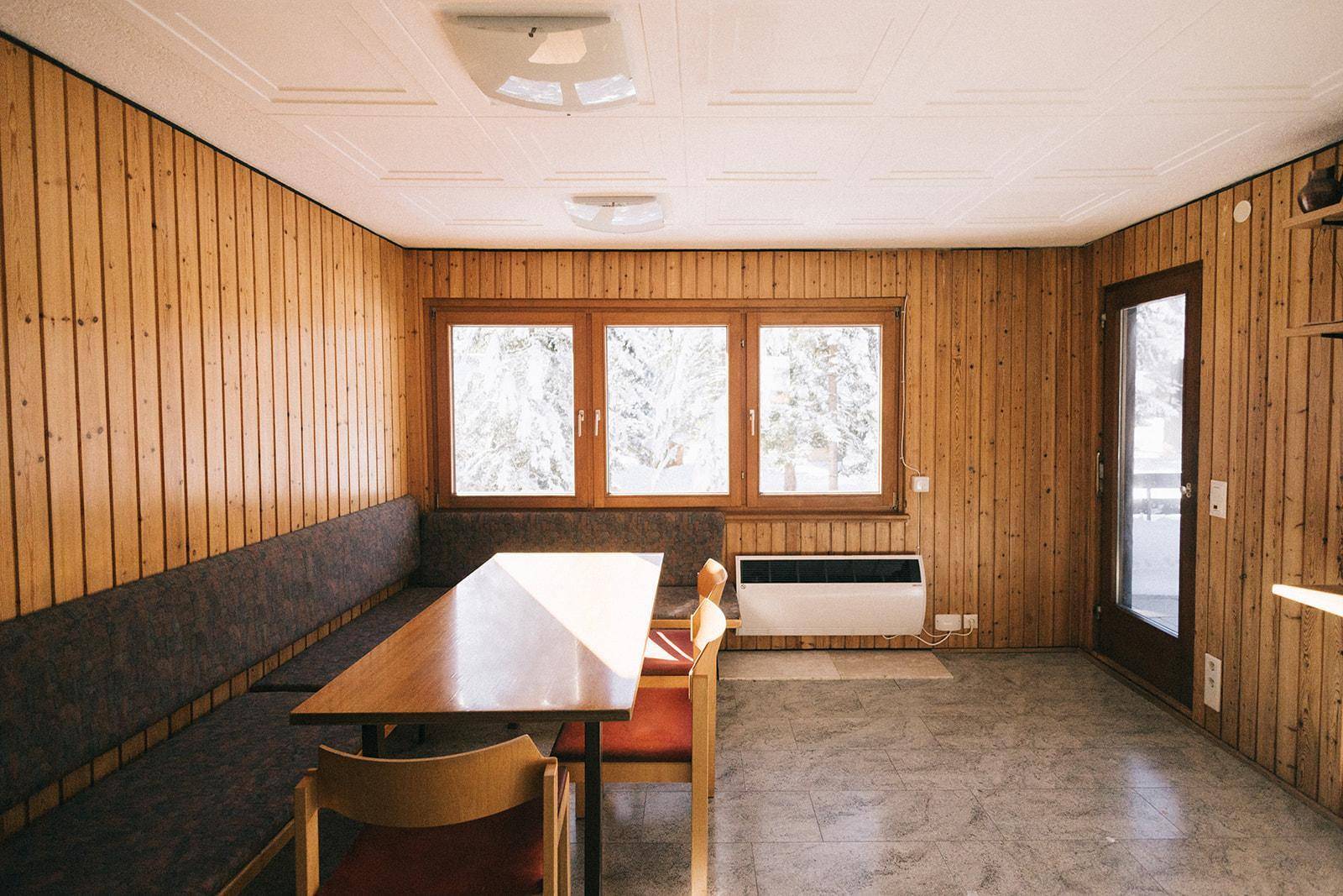 Geräumiger Essbereich mit Holzvertäfelung, langer Sitzbank und großem Fenster, hell und einladend.