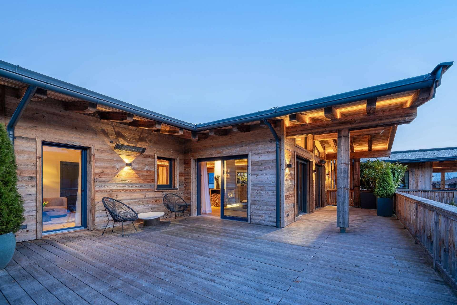 Große Holzterrasse mit Sitzgelegenheiten und Zugang zu den Innenräumen des Chalets.