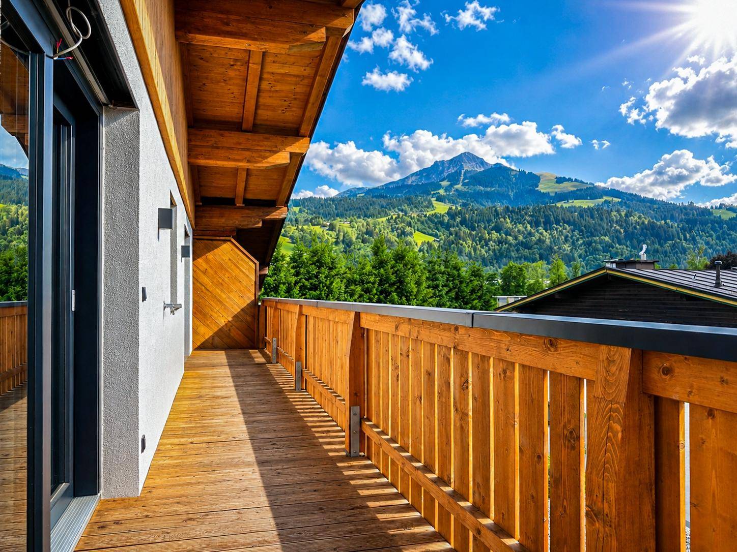 Geräumiger Balkon mit Holzverkleidung und atemberaubendem Blick auf die umliegende Berglandschaft.