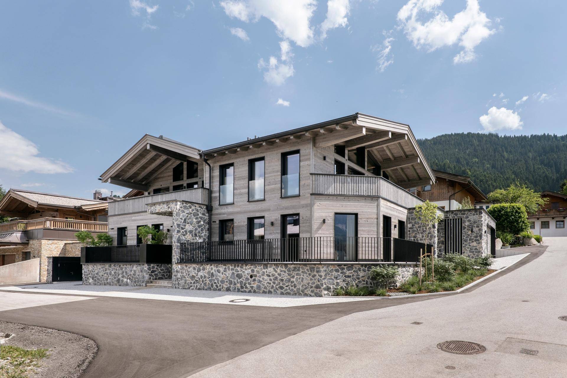 Elegantes Chalet mit moderner Architektur, Steinfassade und Balkonen in sonniger Lage.