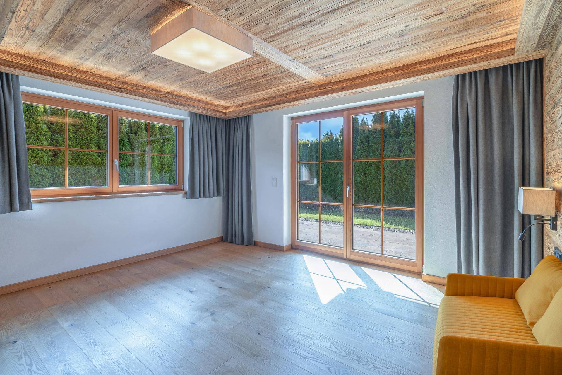 Helles Zimmer mit Holzbalkendecke, Parkettboden und Zugang zum Garten.