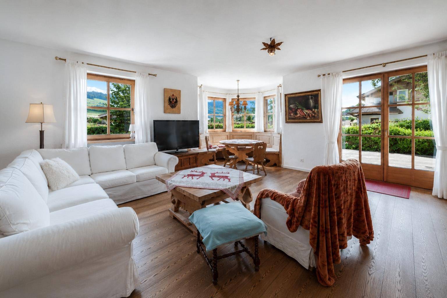 Heller Wohn- und Essbereich mit Holzboden, weißen Sofas und Zugang zur Terrasse.